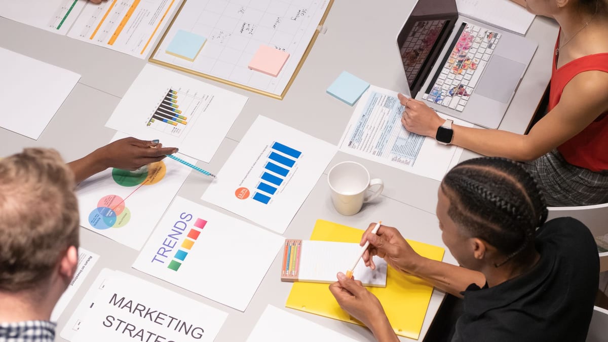 Overhead view of a team with marketing strategy charts, notes and a laptop on a table